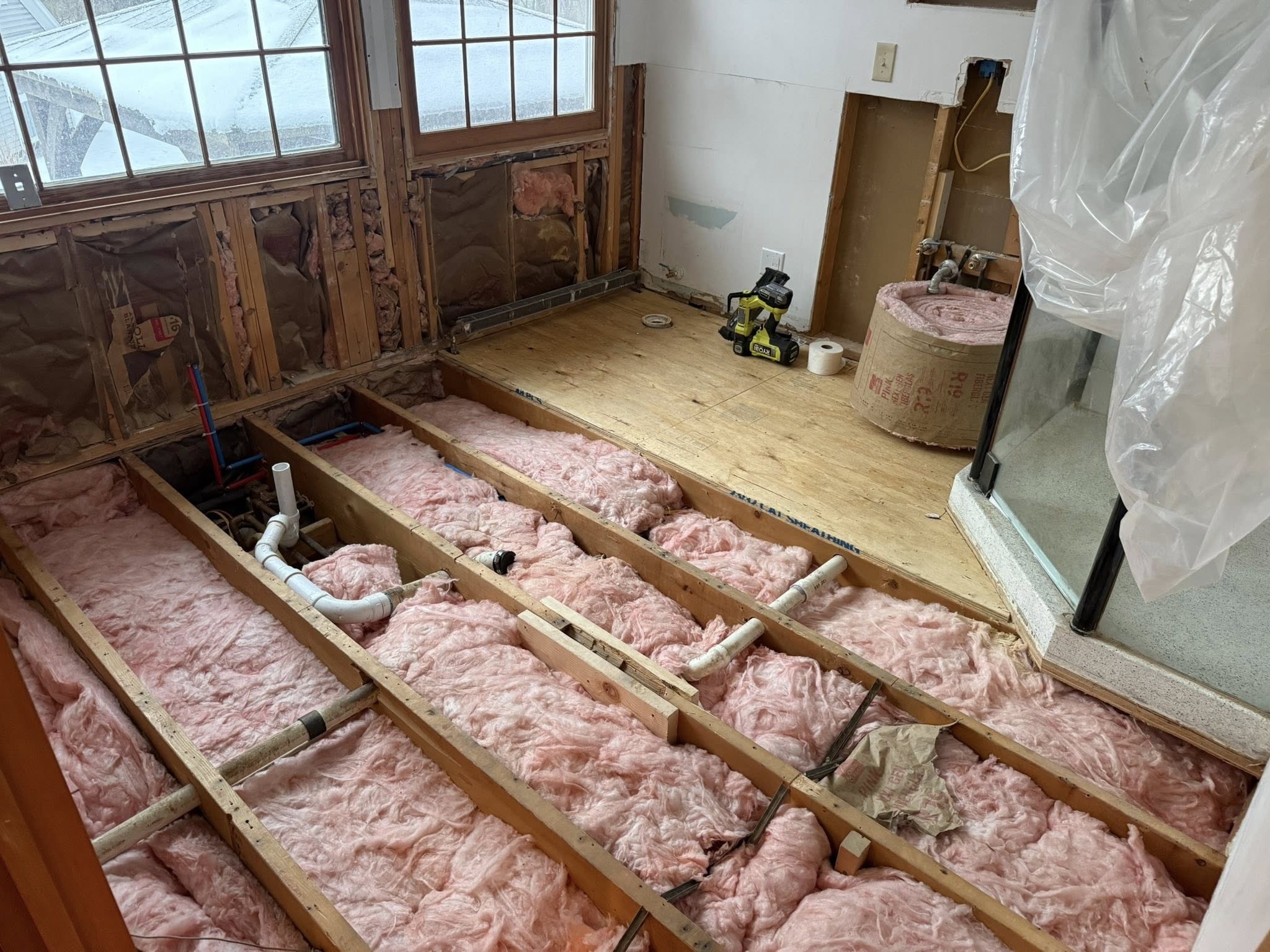 Bathroom demo — subfloor and plumbing exposed