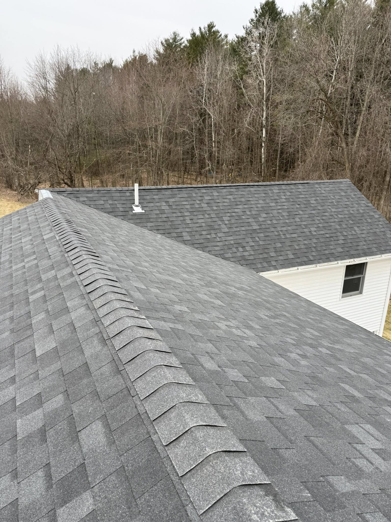 Completed grey architectural shingle roof with crisp ridge cap